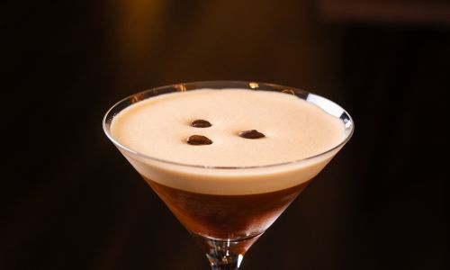 A freshly made espresso martini cocktail in a martini glass, topped with three coffee beans.